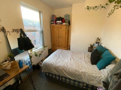 A cozy student bedroom featuring a neatly made ...