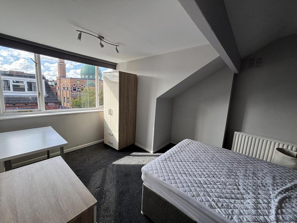 A well-lit, clean bedroom featuring a double be...