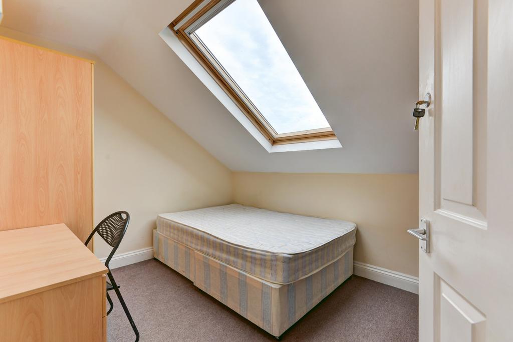 A cozy single bedroom with a sloped ceiling and...