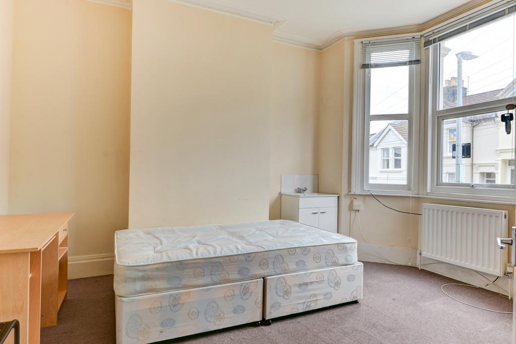 A well-lit bedroom featuring a single bed and a...