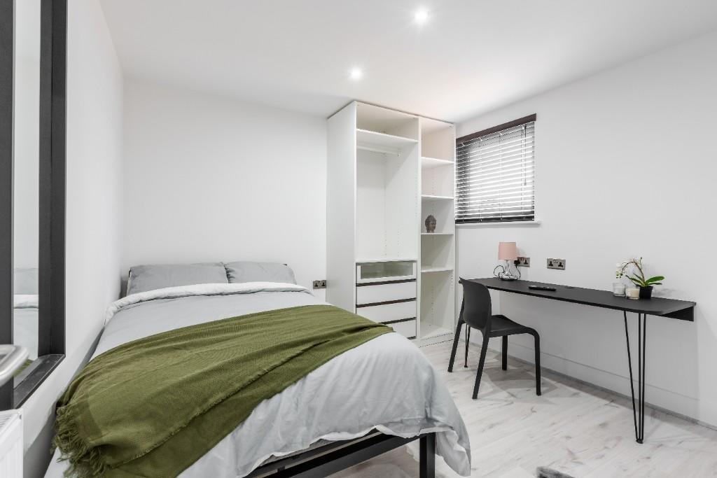 A bright and tidy bedroom featuring a comfortab...