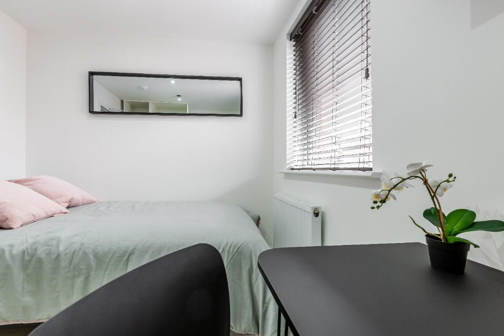 A bright, tidy bedroom featuring a comfortable ...