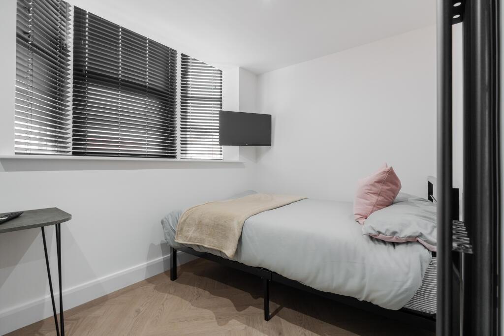 A clean and cozy single bedroom with a neatly m...