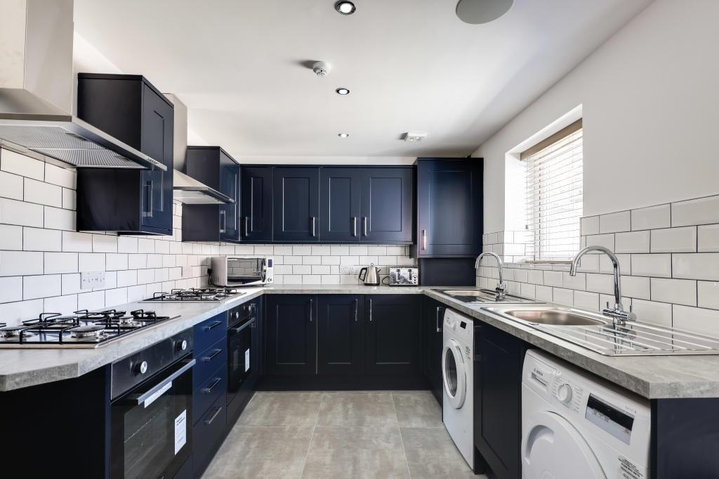 A modern, clean kitchen with sleek dark cabinet...