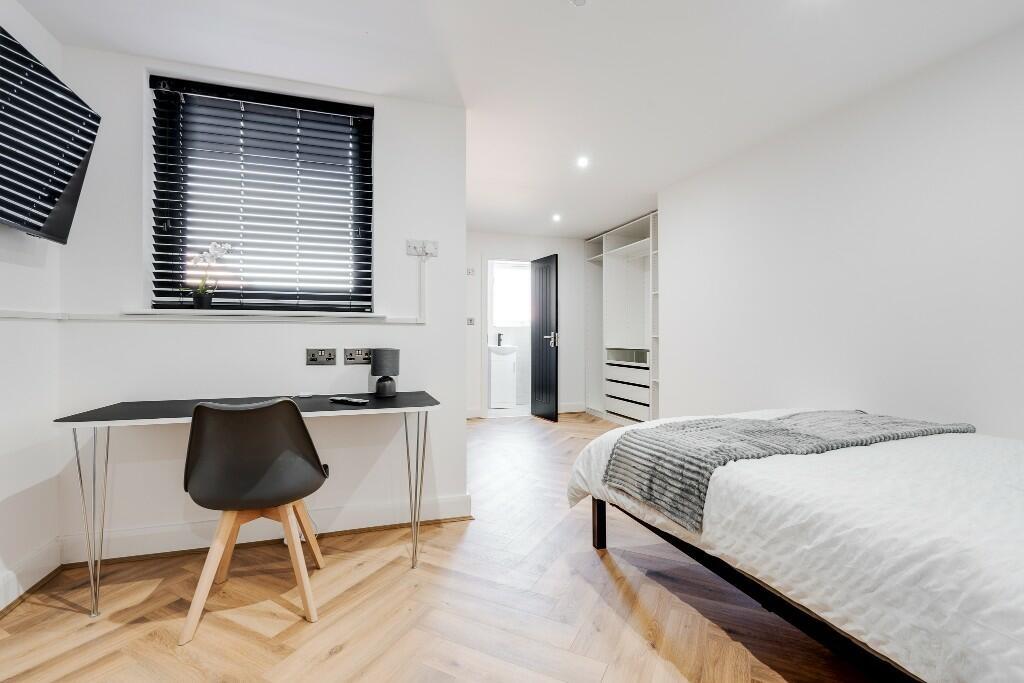 A modern, well-lit bedroom featuring a comforta...