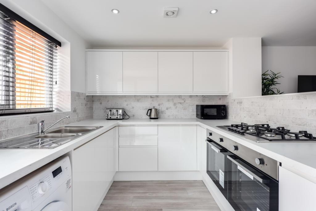 Modern and bright kitchen with white cabinets, ...