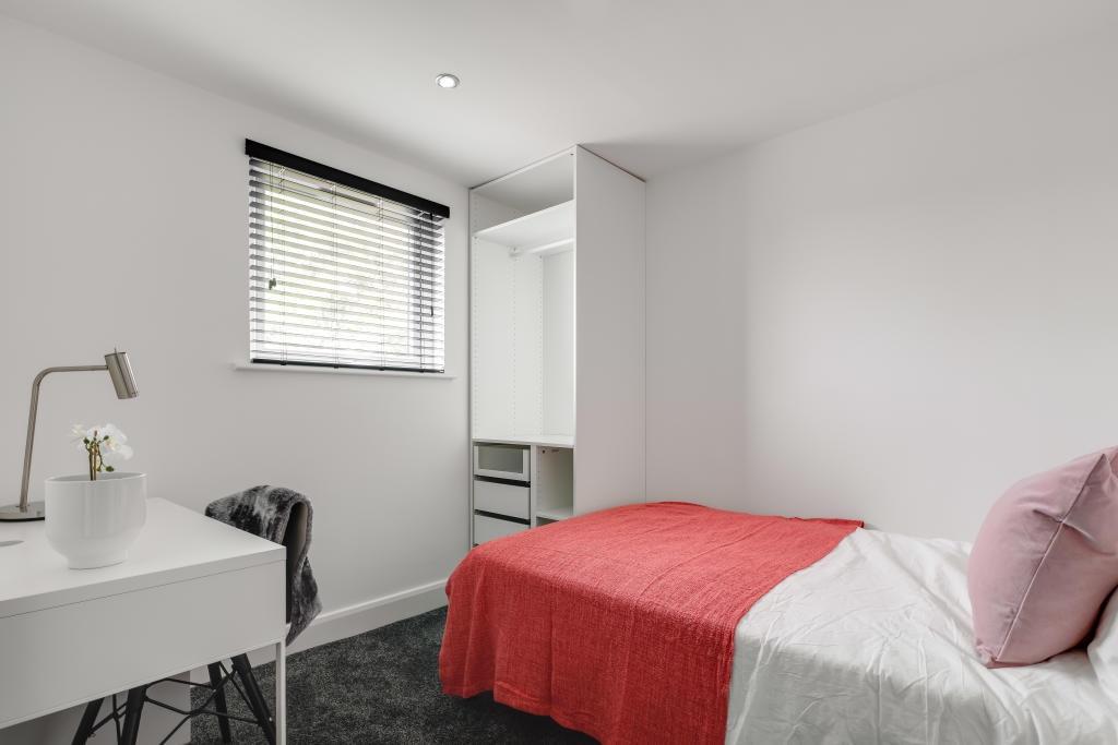 A neatly presented student bedroom with a comfo...