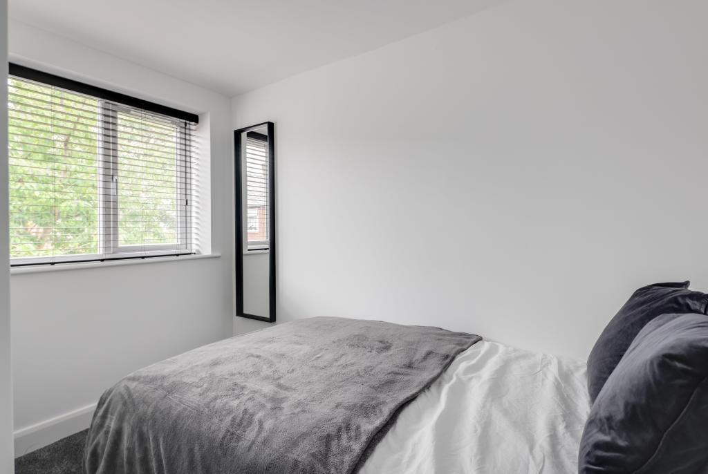 A bright and tidy bedroom featuring a double be...