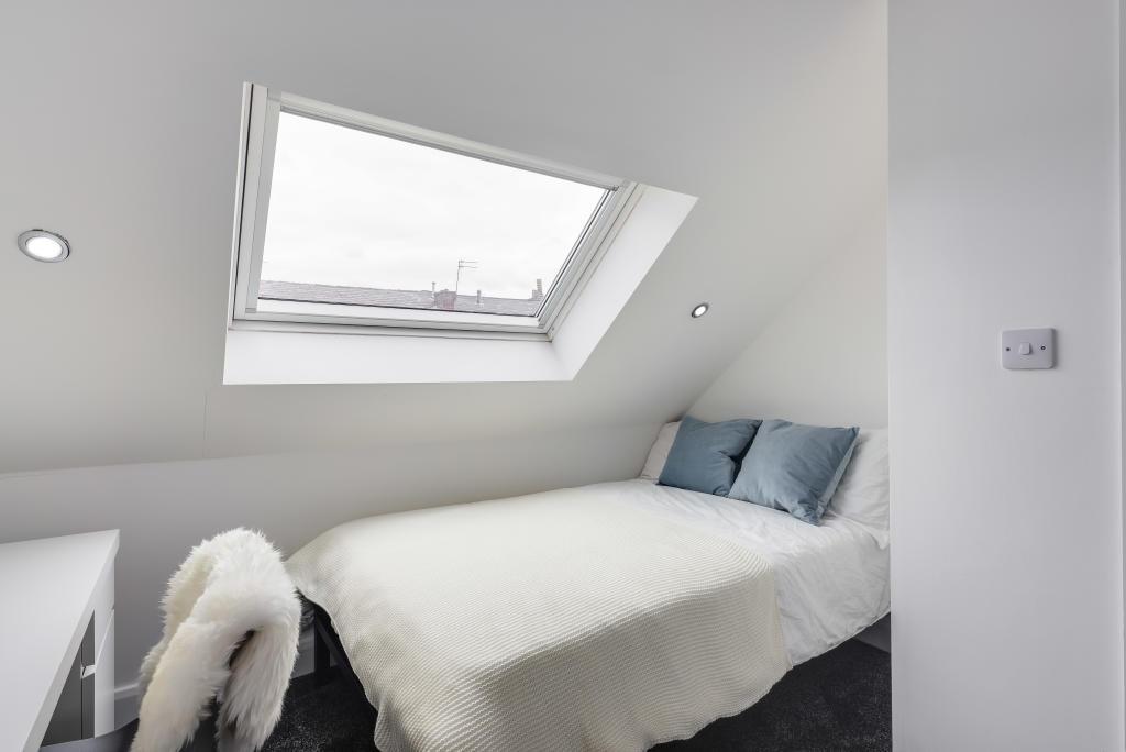 A bright and clean bedroom featuring a comforta...