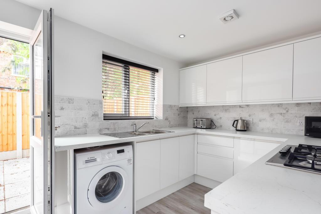 A modern, well-lit kitchen featuring white cabi...