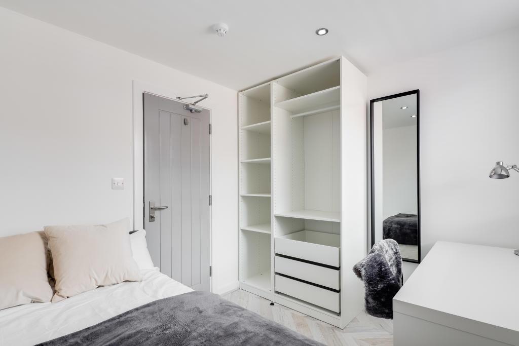 A bright and tidy bedroom featuring a neutral d...