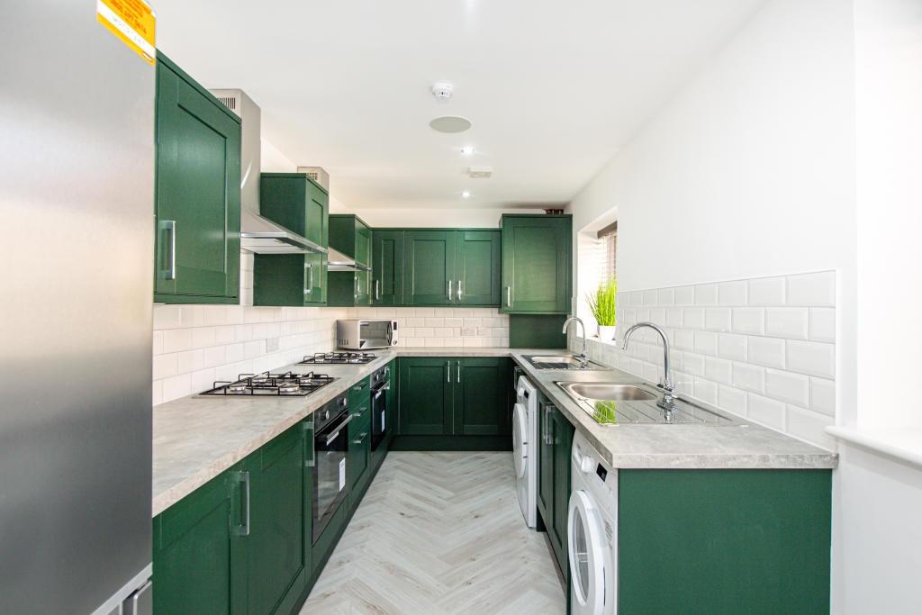 Modern and bright kitchen featuring green cabin...