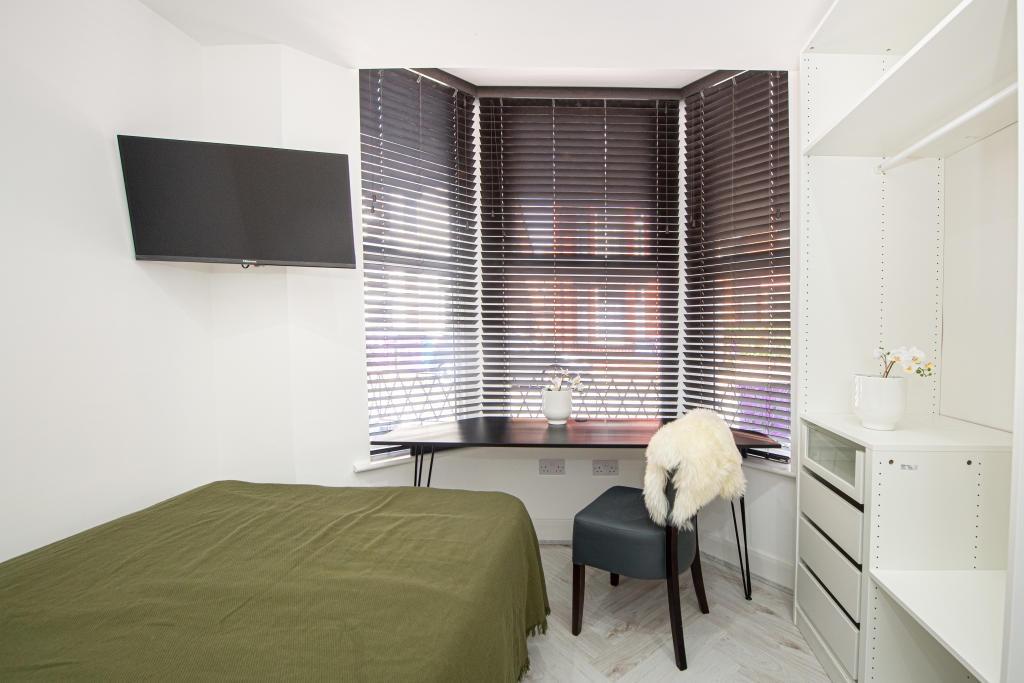 A cozy bedroom featuring a large window with bl...