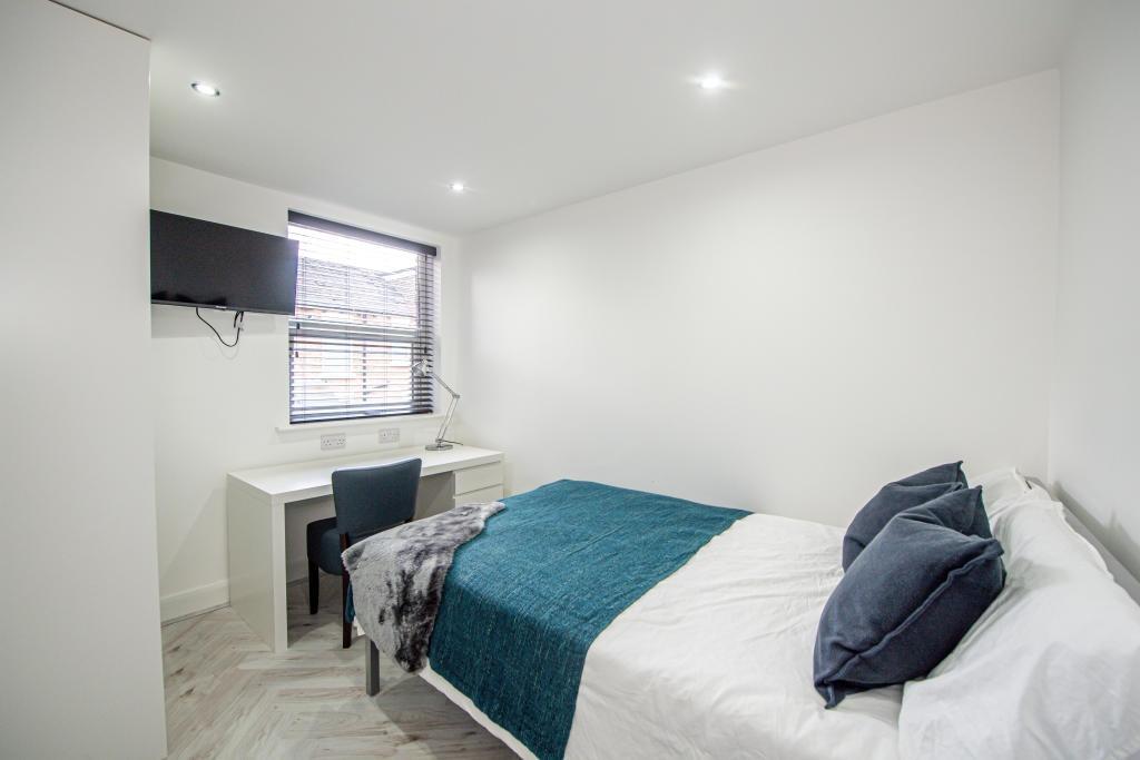 A bright and cozy single bedroom featuring a co...