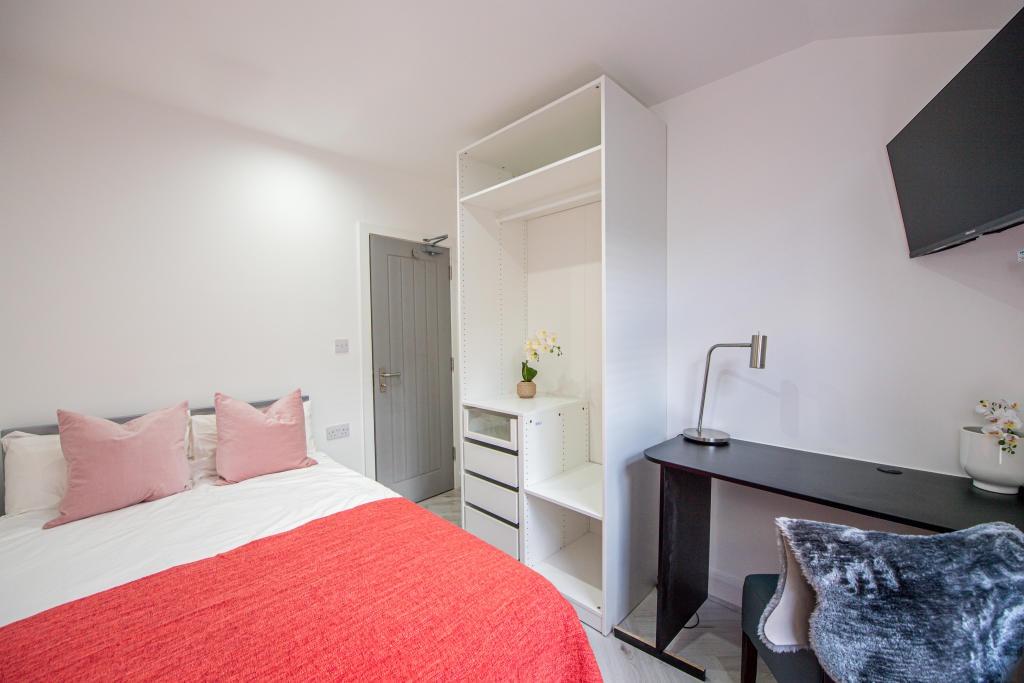 A bright and welcoming bedroom featuring a comf...