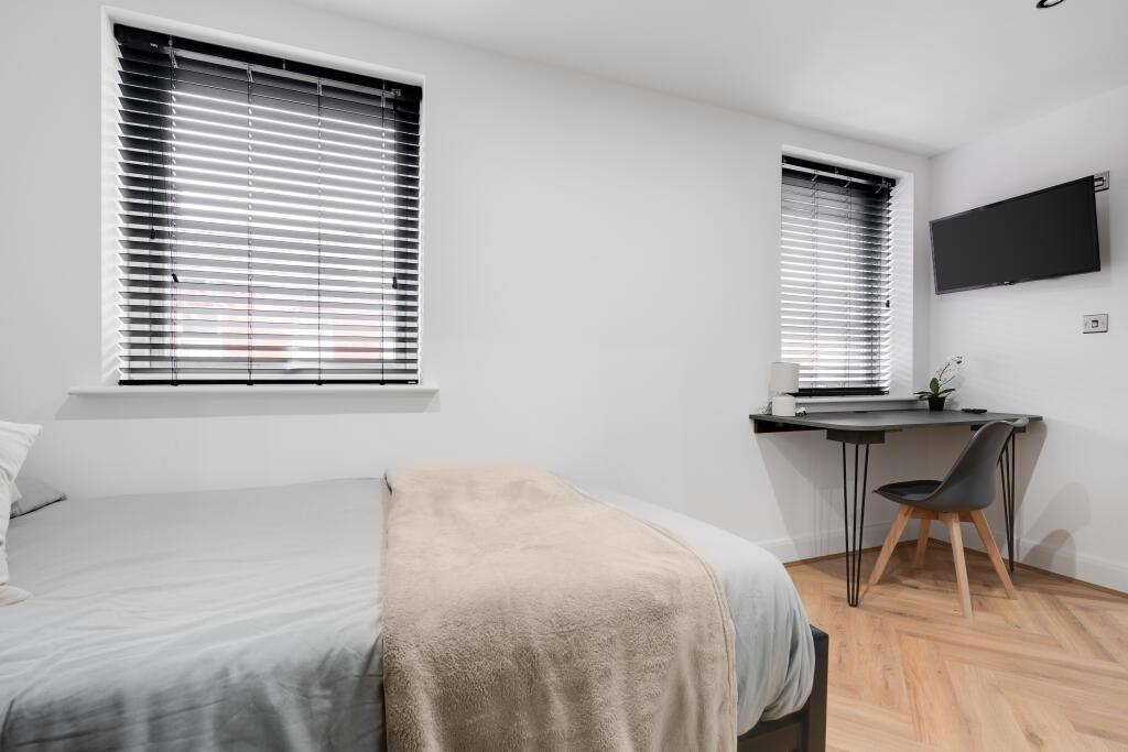 A bright and tidy bedroom featuring a comfortab...