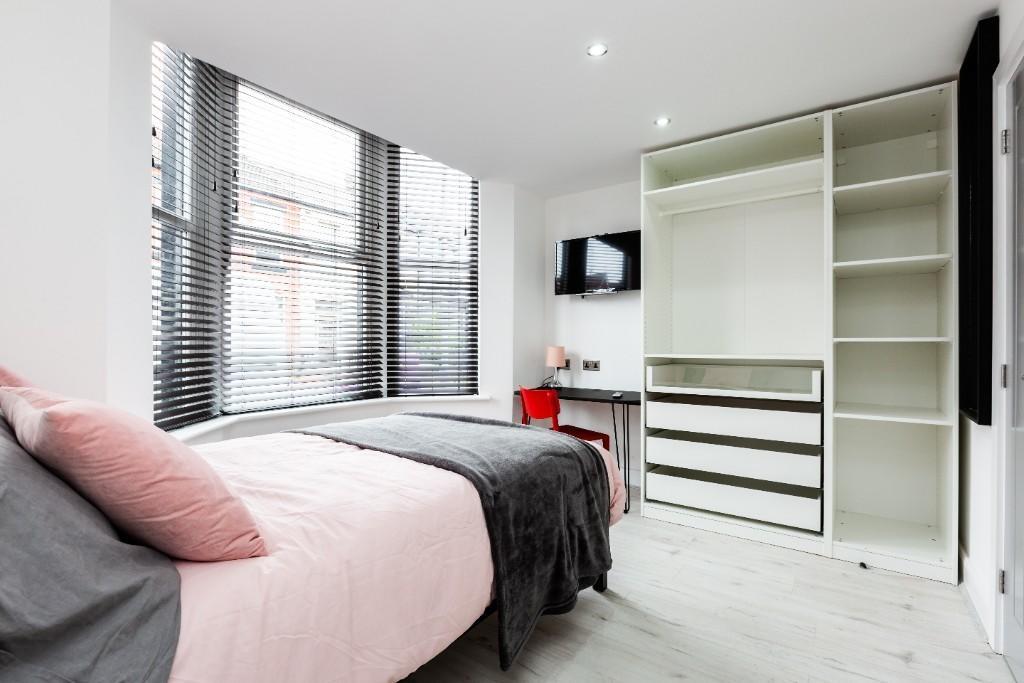 A modern, well-lit bedroom featuring a comforta...