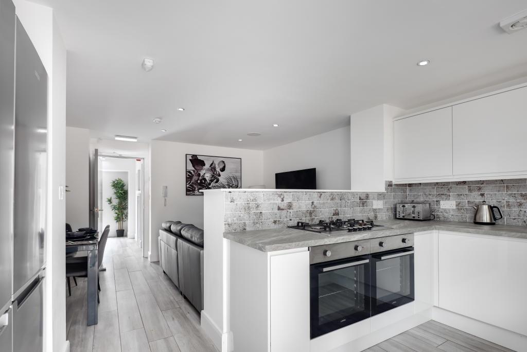 A modern, bright kitchen with white cabinetry a...