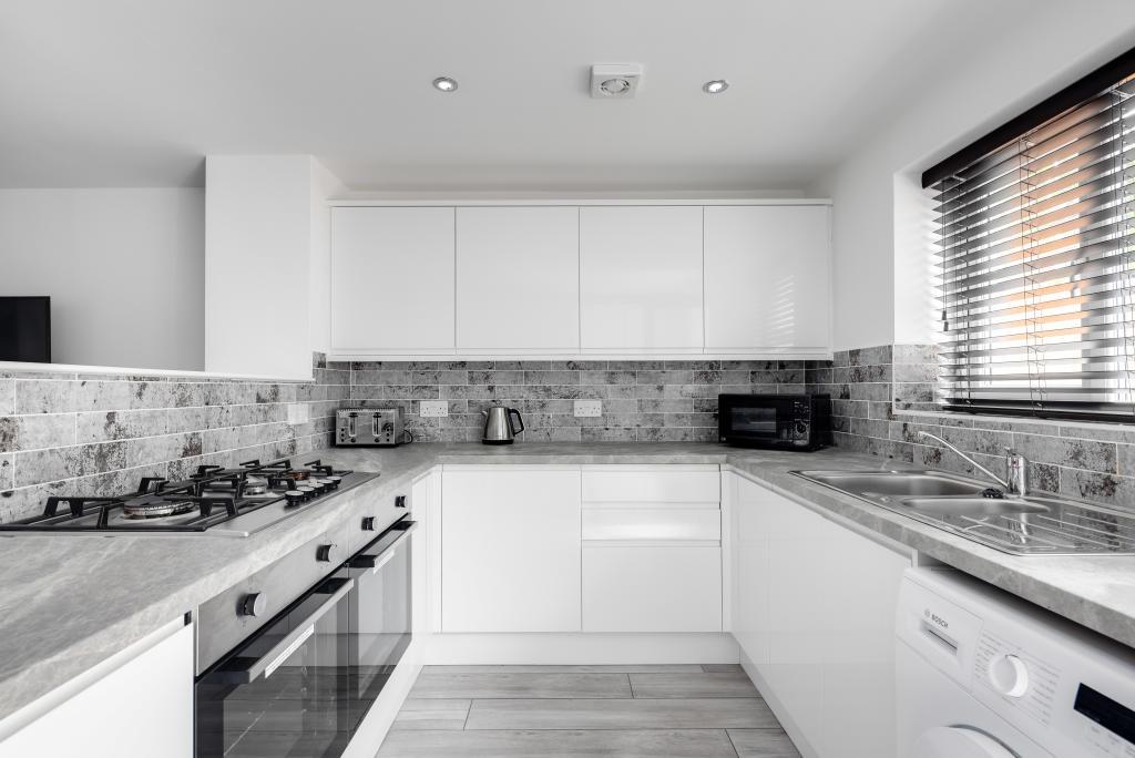 A modern, bright kitchen featuring white cabine...