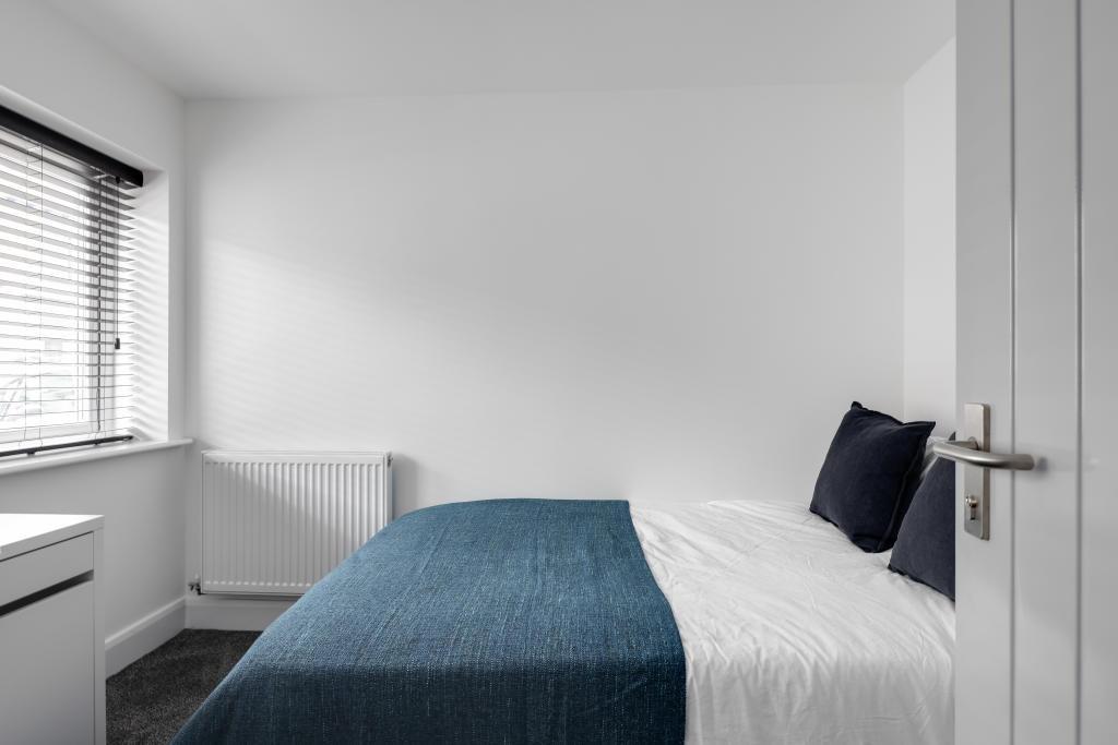 A well-lit and tidy single bedroom featuring a ...