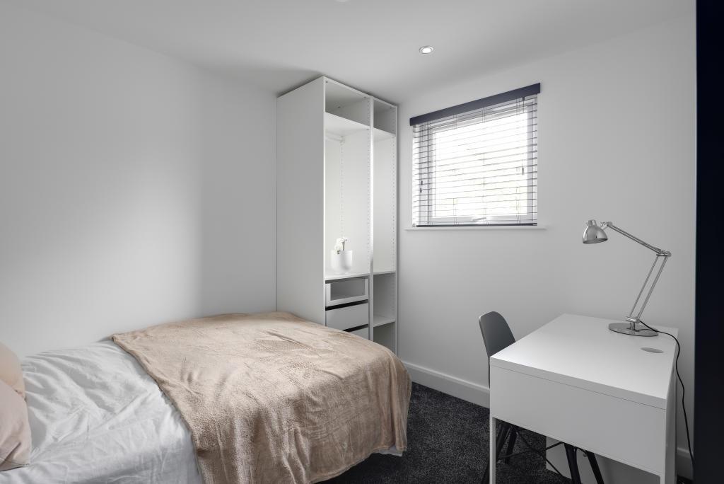 A tidy, well-lit bedroom featuring a single bed...