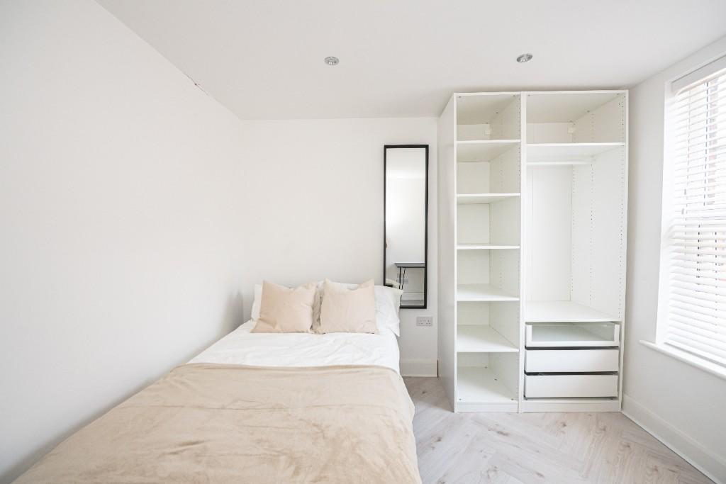 A bright and tidy bedroom featuring a comfortab...