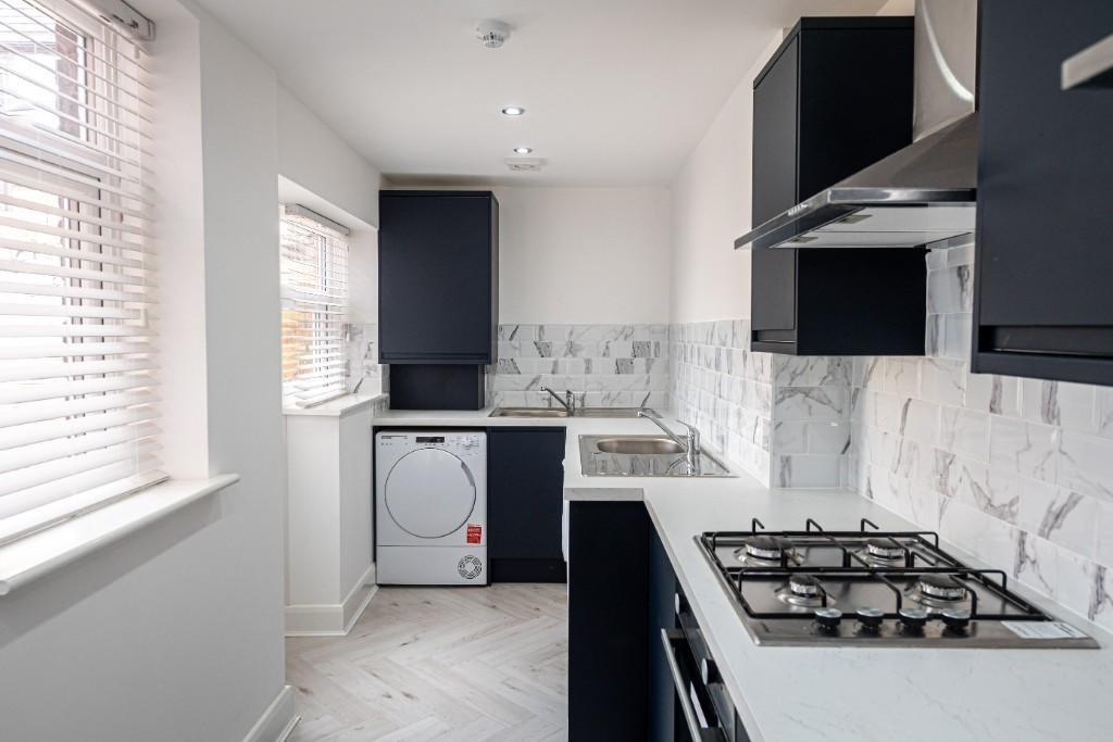 Modern kitchen with sleek dark cabinetry, brigh...