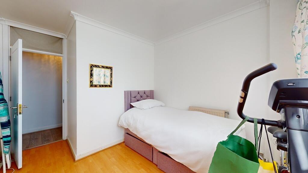 A tidy single bedroom featuring a neatly made b...