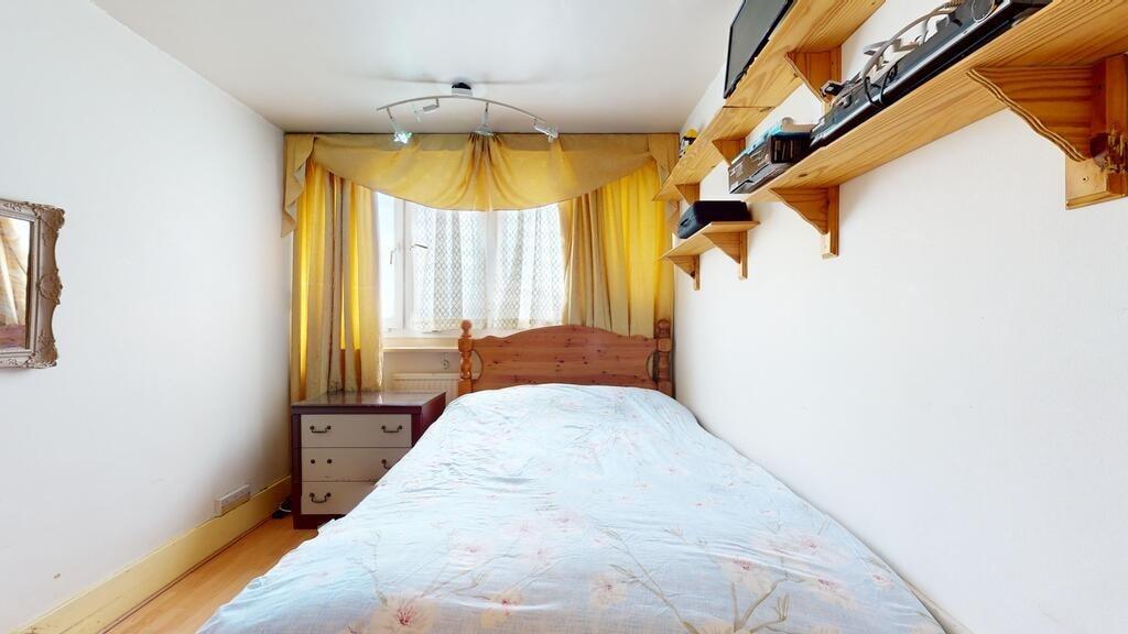 A cozy bedroom featuring a wooden bed frame wit...