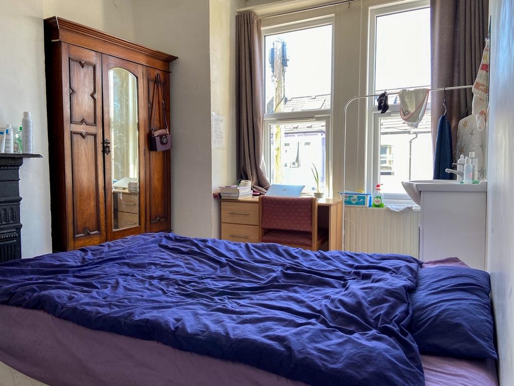 A bright and cozy bedroom featuring a large win...