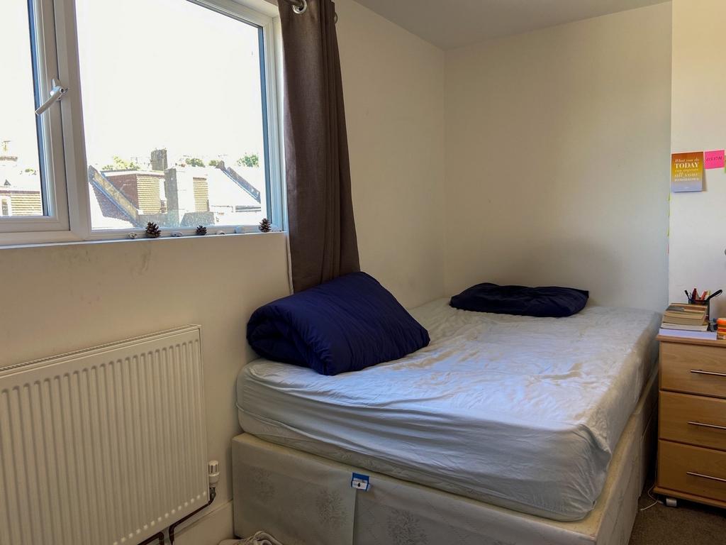 A cozy single bedroom featuring a single bed wi...