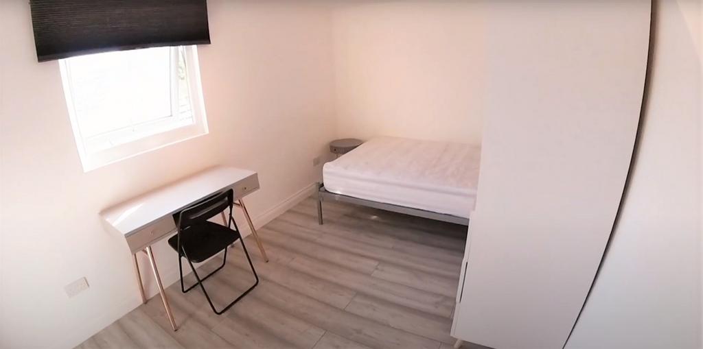 A neat and well-lit bedroom with a single bed p...
