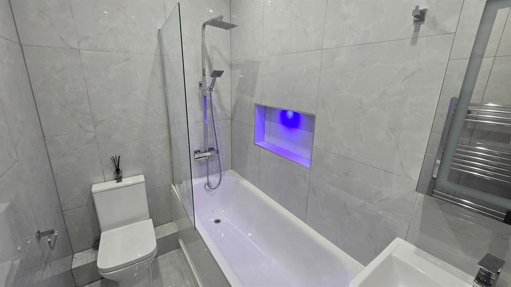 A modern, clean bathroom featuring a bathtub wi...