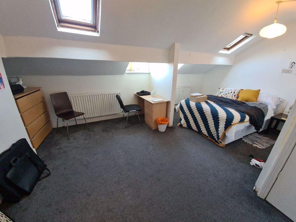 A well-lit bedroom featuring a double bed with ...