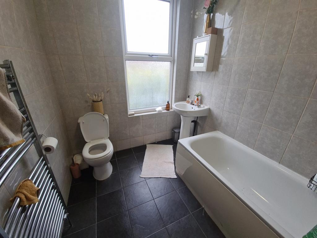 A bright and clean bathroom featuring a bathtub...
