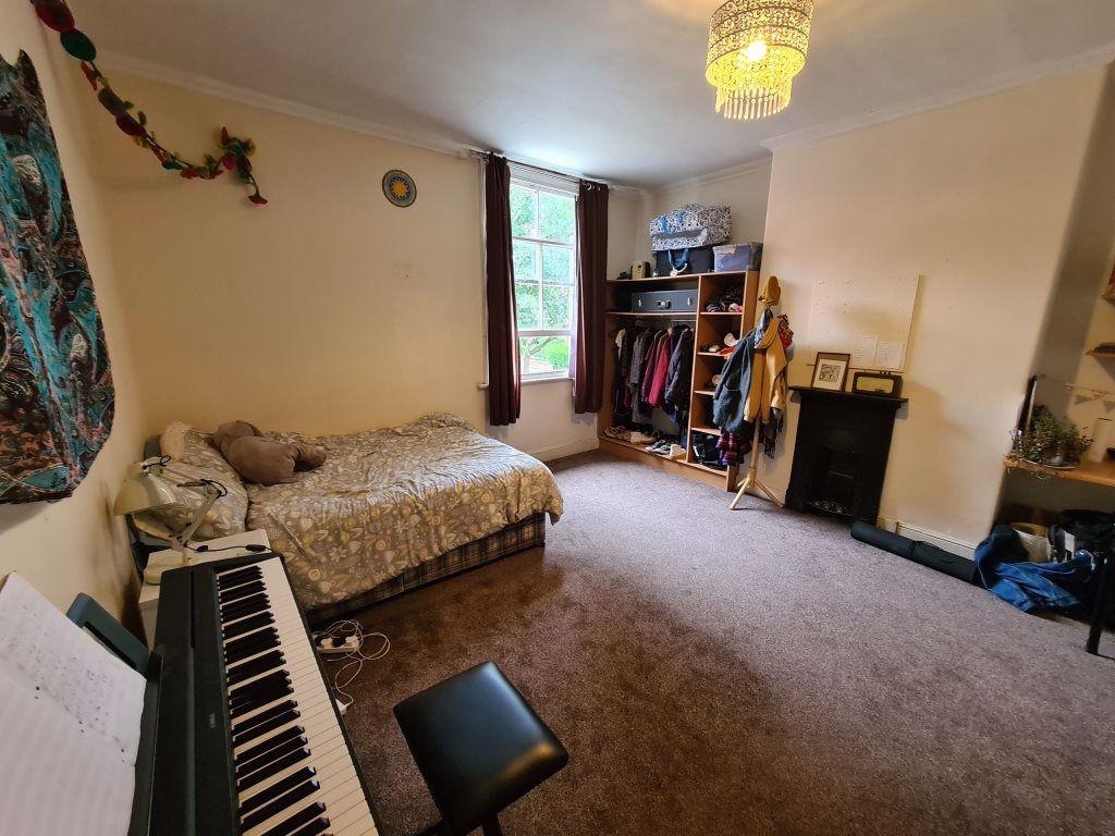 A cozy bedroom featuring a single bed, a window...