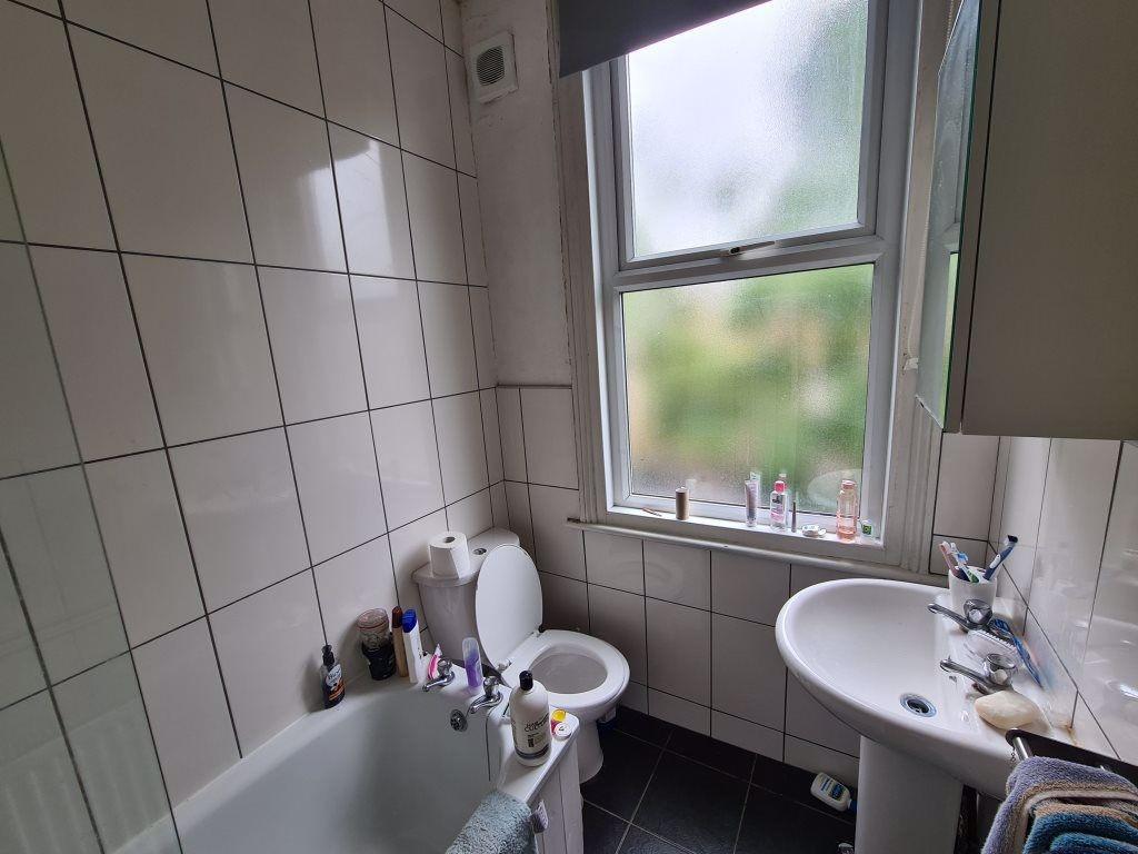 A clean and bright bathroom featuring a bathtub...