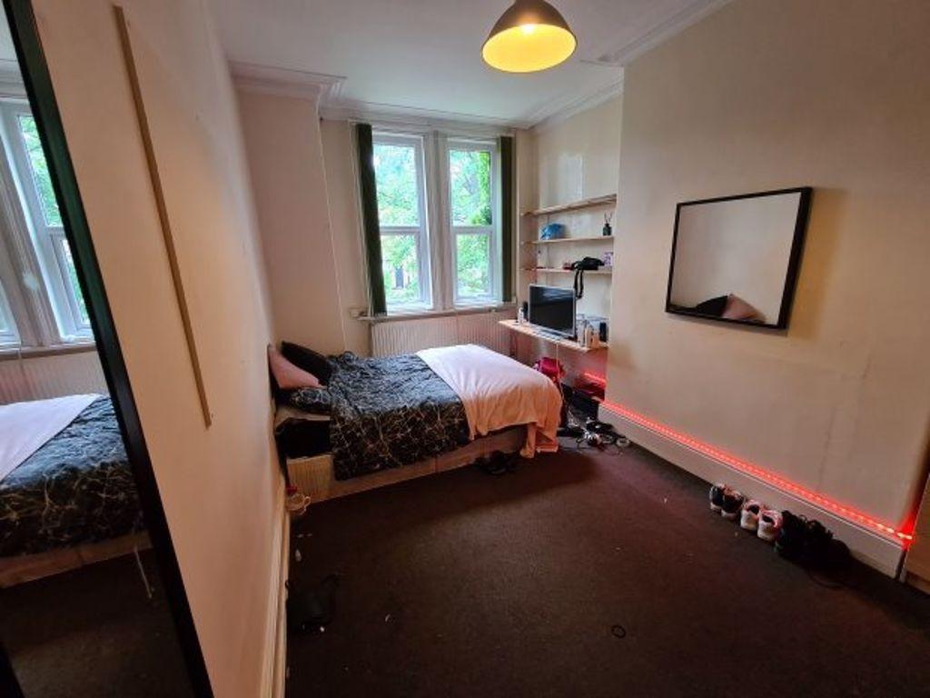 A cozy single bedroom featuring a bed, a window...