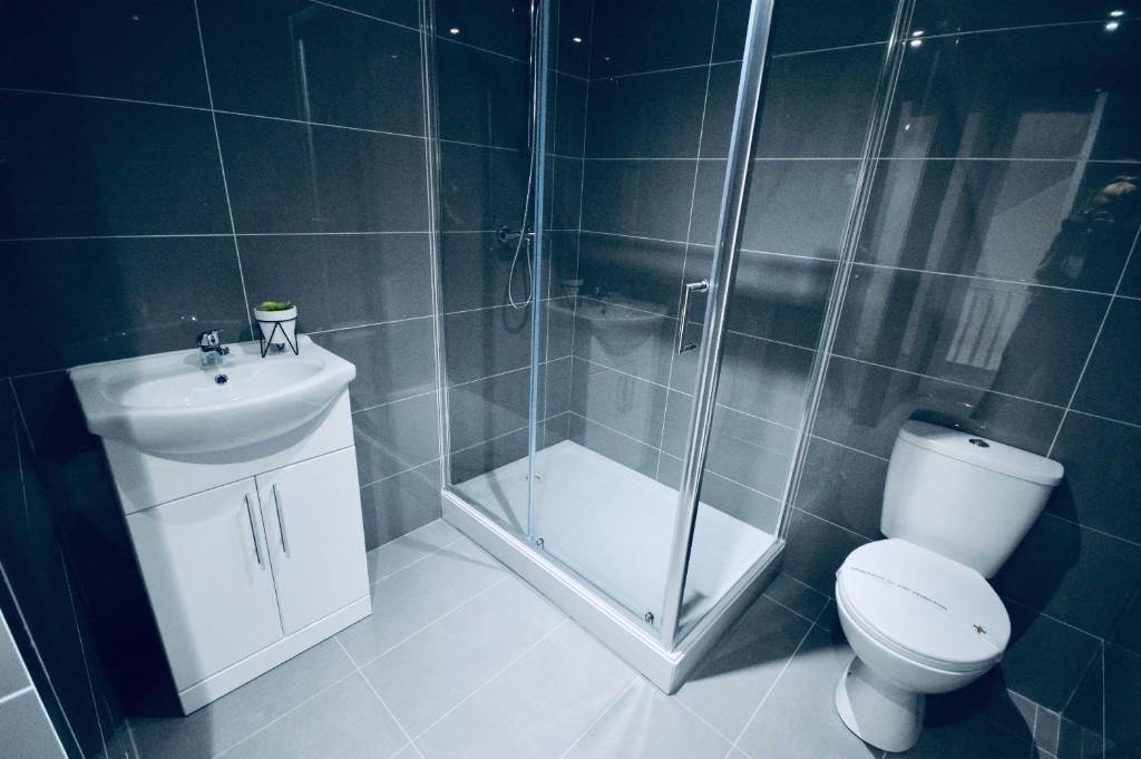 A modern bathroom featuring a spacious shower e...