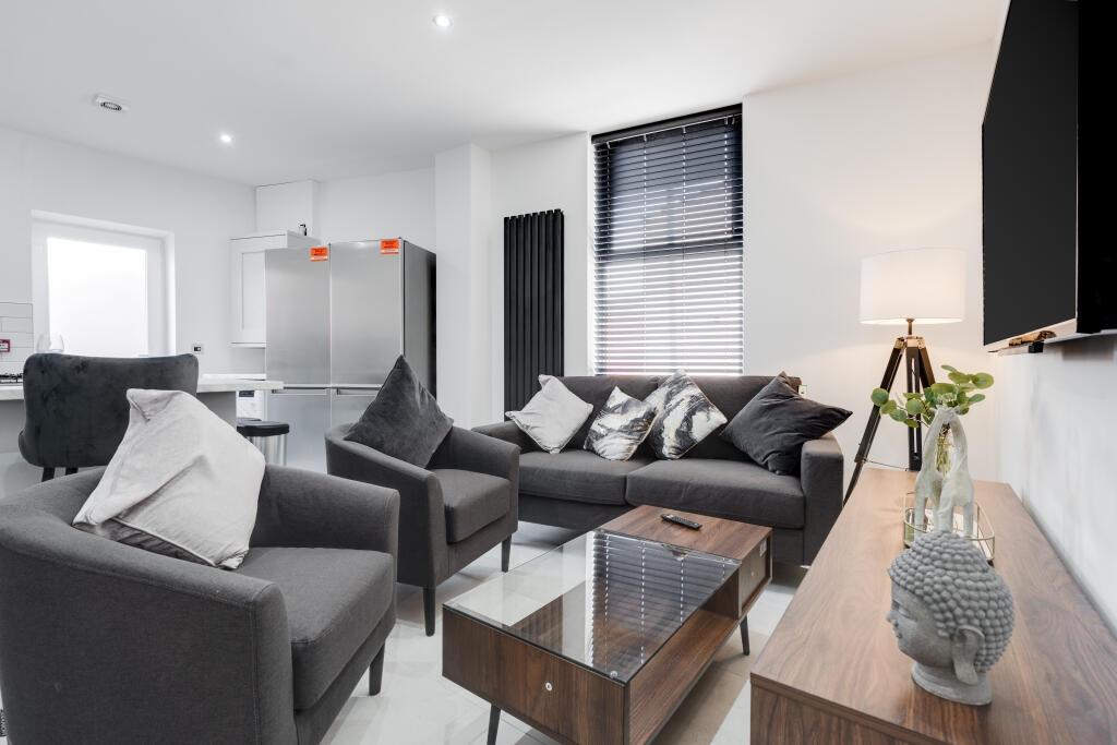 A spacious, modern living room featuring comfor...