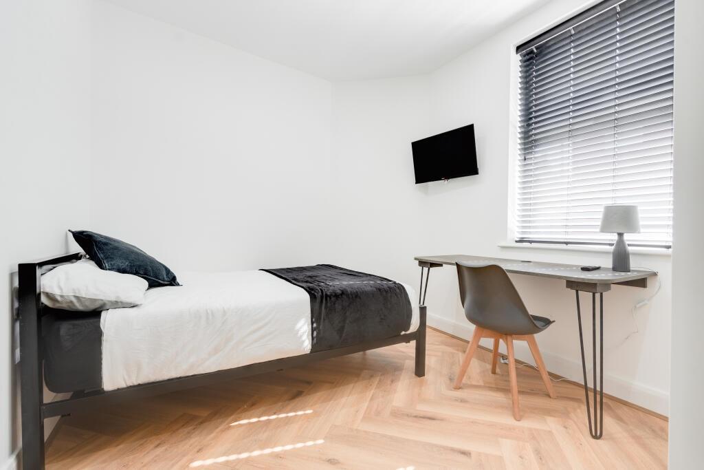 A tidy and well-lit single bedroom featuring a ...