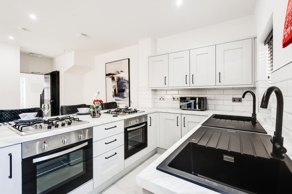 A modern kitchen with white cabinetry and black...