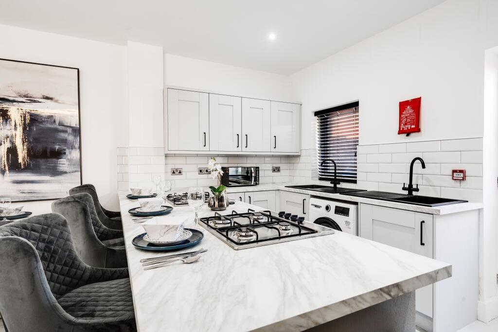A modern, bright kitchen with white cabinetry a...