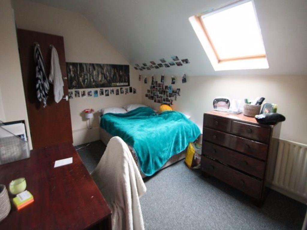 A cozy single bedroom with a bed covered in a b...