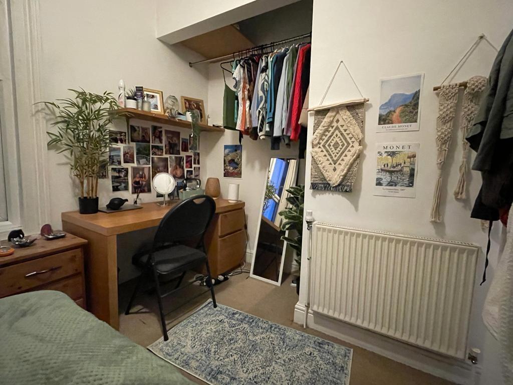 Cozy furnished bedroom with a desk workspace, b...