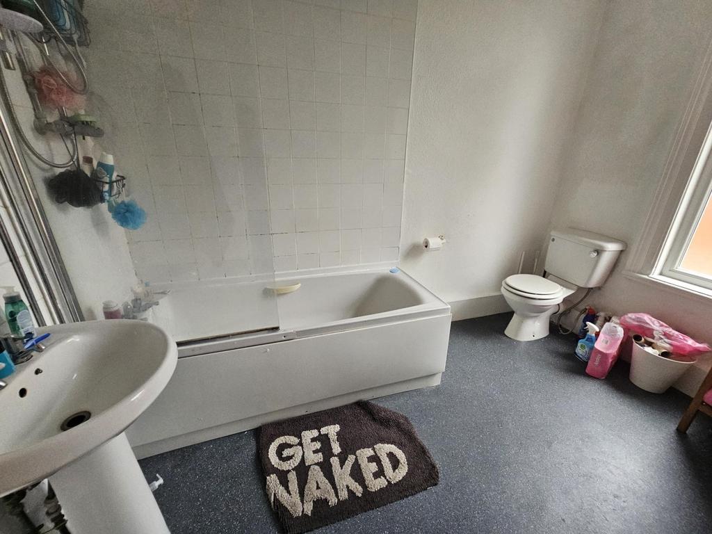 A clean and bright bathroom with a bathtub, toi...