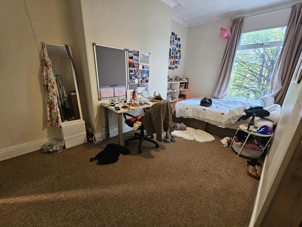 A cozy bedroom featuring a single bed near the ...