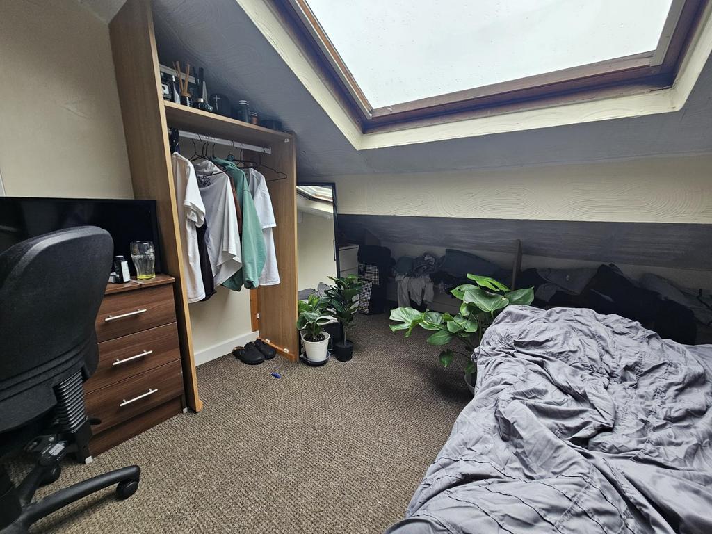 A bright and cozy bedroom featuring a sloped ce...