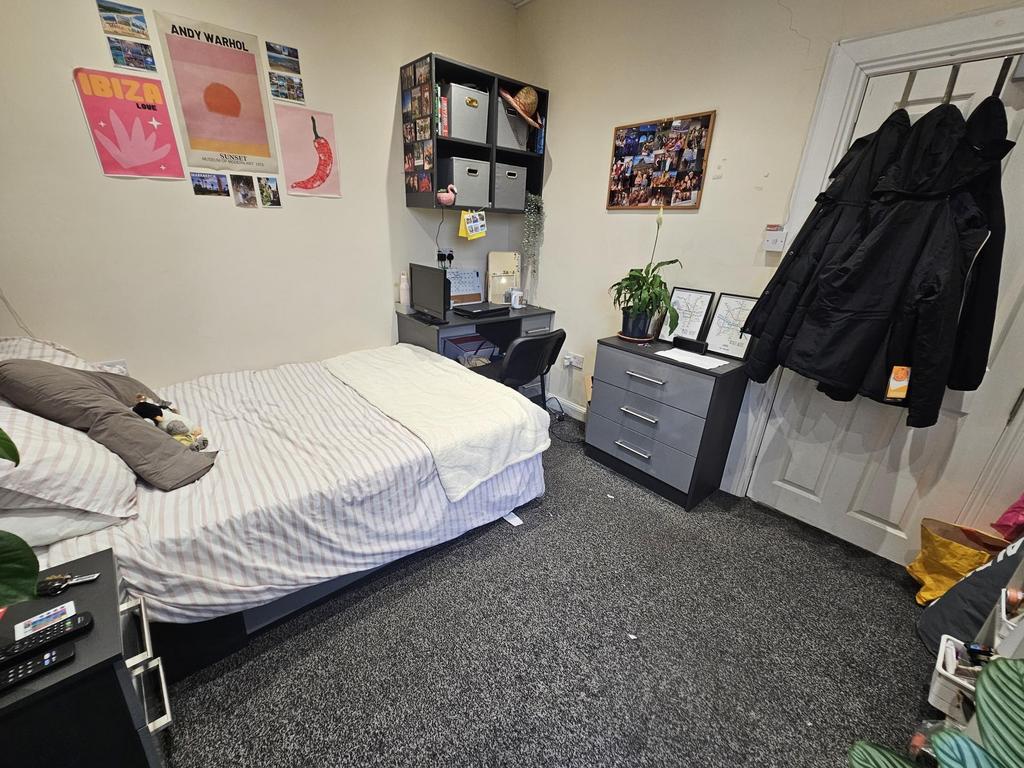 A well-maintained bedroom with a large bed, des...