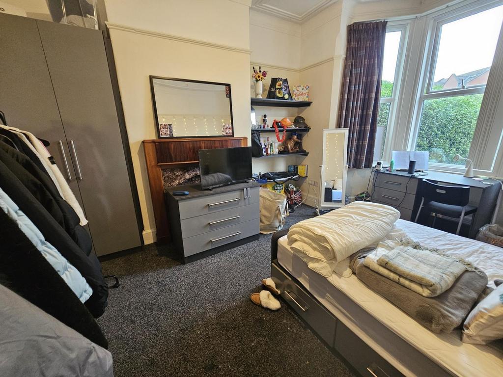 A cozy bedroom with a neatly made bed, ample na...